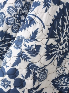 Macro detail of blue floral quilted fabric with botanical pattern and wavy stitching