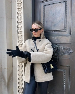 Look de rue d'un manteau en fausse fourrure beige avec liserés en cuir noir et boutons
