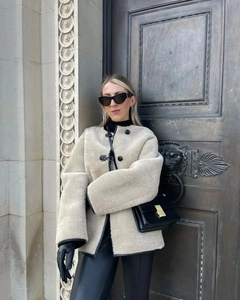 Détail du manteau en fausse fourrure à boutonnage simple avec liseré en cuir contrasté