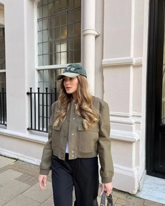 Detail of khaki bomber jacket featuring large flap pockets and ribbed cuffs in street style