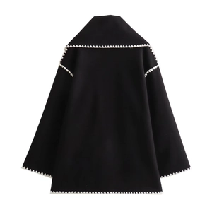 Detail view of the black loose jacket featuring white zigzag lace trim on collar and cuffs