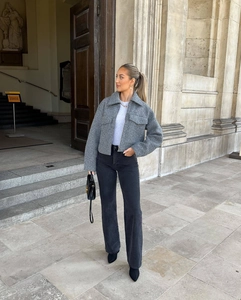 Detailed street style view of a grey cropped wool jacket with black jeans and leather handbag