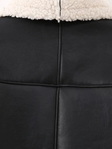 Détail d'une veste en similicuir noir avec col en peau de mouton blanche et surpiqûres