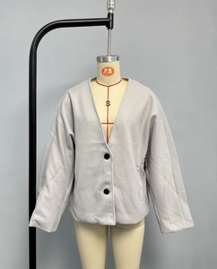 Détail de la texture en laine gris clair et des grands boutons noirs sur la veste col V