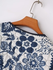 Close-up of blue and white floral quilted jacket collar with round neckline and navy piping