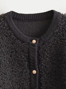 Close-up of black sherpa cardigan with golden embossed lion head buttons and ribbed collar