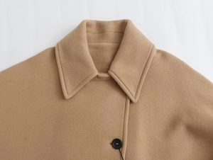 Detail of notch lapel and twill wool texture on a camel short coat with black button