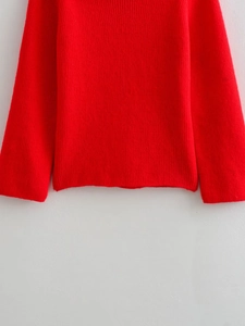 Detail of red knit sweater featuring vertical ribbed texture and elastic hem and cuffs