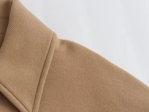 Close-up detail of a camel wool coat collar showing thick twill weave texture