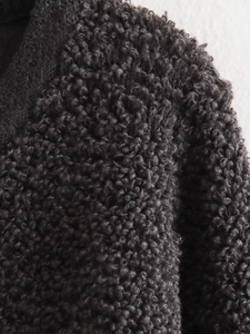 Close-up of high-quality dark grey curly teddy fleece fabric texture and warm fiber detail