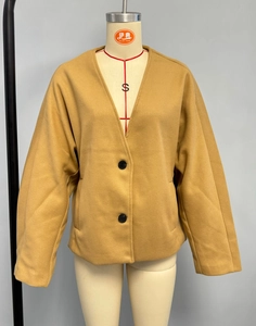 Détail d'un manteau en laine jaune moutarde montrant le col en V et les gros boutons noirs