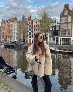 Détail d'un manteau beige en fausse fourrure avec boutons brandebourgs noirs