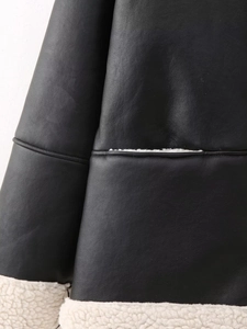 Détail d'une veste en similicuir noir avec poignets en laine blanche et coutures soignées