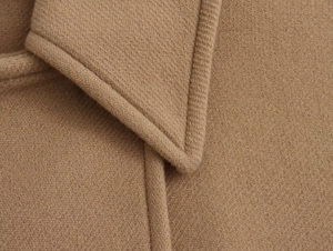 Detailed macro view of the lapel and fine twill texture on a camel wool blend coat