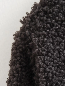 Detailed close-up of dark grey boucle knit fabric texture for winter knitwear cardigan