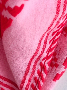 Detail of red and pink crochet knit fabric showing intricate stitch textures and patterns
