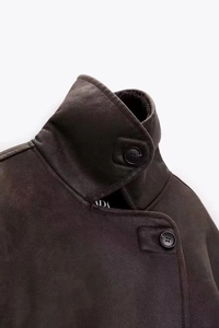 Close-up of stand-up collar with black buttons on a dark brown shearling jacket