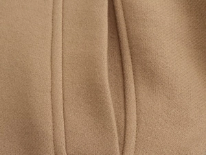 Close-up of high-quality wool blend fabric with neat stitching on a khaki coat