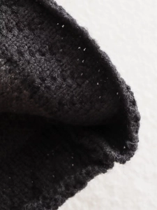 Detailed macro view of black knit texture and fine stitching on a soft wool blend cardigan