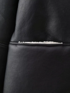 Détail du cuir synthétique noir avec doublure en peau de mouton blanche sur veste décontractée