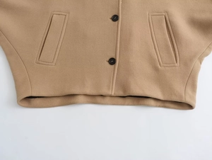 Detail view of khaki wool blend short coat with black buttons and sleek pockets