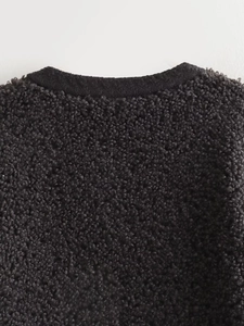 Detailed close-up of dark grey teddy fleece texture with black knitted edge detailing