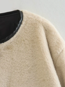 Gros plan d'un manteau en fausse fourrure beige avec garniture en cuir noir et texture