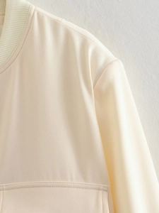 Close-up of ribbed knit collar and high-quality twill fabric on beige bomber jacket