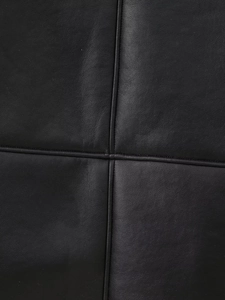 Détail macro de veste en cuir noir avec surpiqûres en croix et texture de qualité