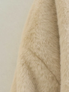 Gros plan d'un manteau en fausse fourrure beige avec des détails de coutures horizontales
