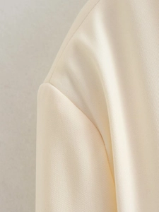 Close-up of cream twill fabric texture and shoulder stitching on a bomber jacket