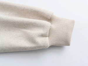 Detailaufnahme der Rippbündchen und Fleece-Textur an der beigen Bomberjacke