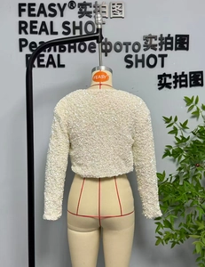 Vista detallada de la chaqueta corta blanca con lentejuelas y texturas brillantes