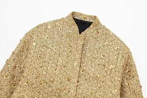 Detailed macro view of golden tweed jacket with sequins and floral design accents