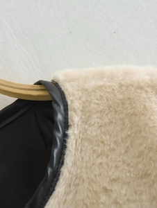 Détail du manteau en fausse fourrure avec bordures en similicuir noir et couture du col