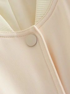 Close-up of ribbed knit collar and matte button on a light pink bomber jacket