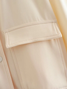 Macro view of twill fabric texture and flap pocket detail on a beige bomber jacket