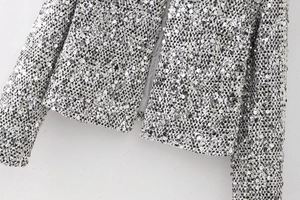 Detailed close-up of shiny silver sequins on textured tweed fabric for women's blazer