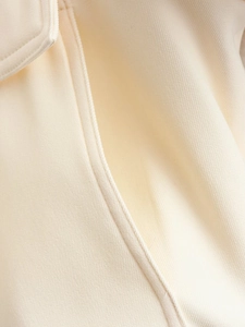 Close-up of premium beige twill fabric texture and stitching details on bomber jacket