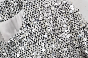 Macro shot of silver sequins on black and white tweed fabric with satin lining detail