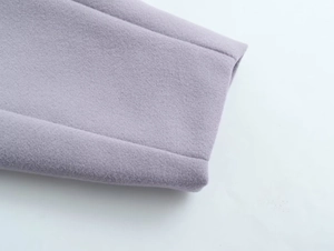 Détail de la manche d'un manteau en laine lavande avec coutures soignées et texture épaisse