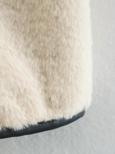 Gros plan détaillé sur la texture de fausse fourrure crème et la finition en cuir noir