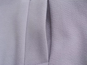 Détail des coutures plates et de la poche latérale sur cette veste en laine lavande