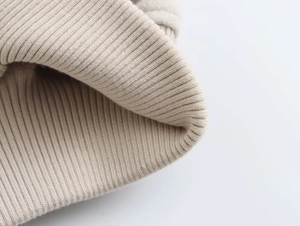 Detailaufnahme der beigen Rippstrick-Textur einer modischen kurzen Bomberjacke
