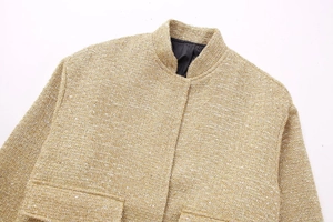 Detail shot of champagne gold tweed jacket showing stand collar and sequin texture