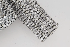 Detailed macro view of black and white tweed fabric with silver sequins on sleeve cuff