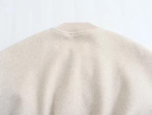 Detail von beigem Rippstrickkragen und weicher Wolltextur an einer modischen Bomberjacke