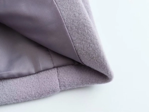 Détail de l'ourlet du manteau en laine lilas avec coutures soignées et doublure satin