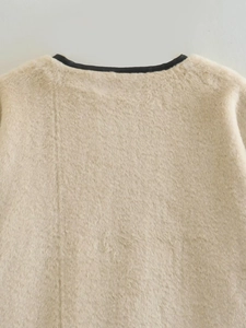 Détail de veste en fausse fourrure crème avec bordure noire au col rond contrastée