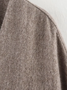 Macro shot of high-quality wool fabric texture and shoulder seams on a taupe coat
